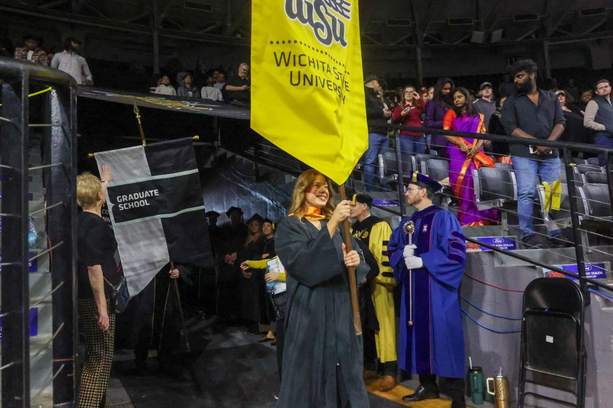 SGA President Kylee Hower leads out the graduates. Hower carried the Wichita State banner.