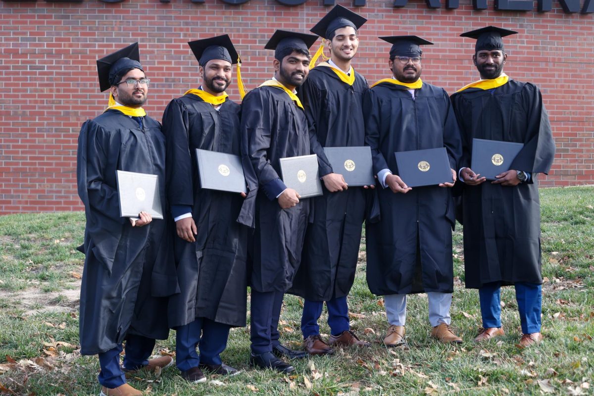 Six graduates take a picture with their diplomas.