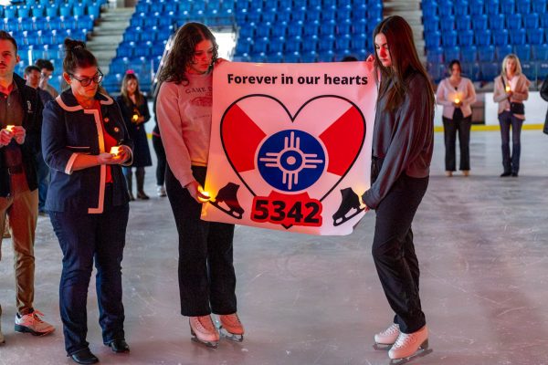 Taylre McPherson and Allison Jabara hold a sign at the Wichita Ice Center vigil. McPherson and Jabara are members of the Wichita Figure Skating Club.