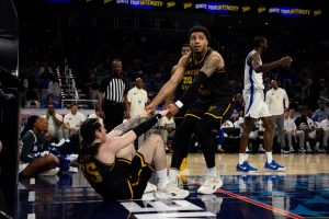 Senior Ronnie DeGray III helps senior Bijan Cortes off the ground after a contested layup from Cortes. DeGray finished with eight defensive rebounds and one offensive rebound in the 83-80 loss against Memphis on March 14.