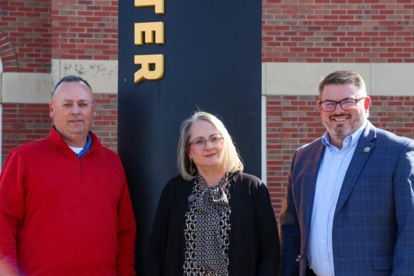 Senior Director of Development for Planned Giving Aaron Winter, Lynette Murphy and Executive Director of Planned Giving Byron Rupp stand in front of the Woodlawn Alumni Foundation. All have included Wichita State in their estate plans.