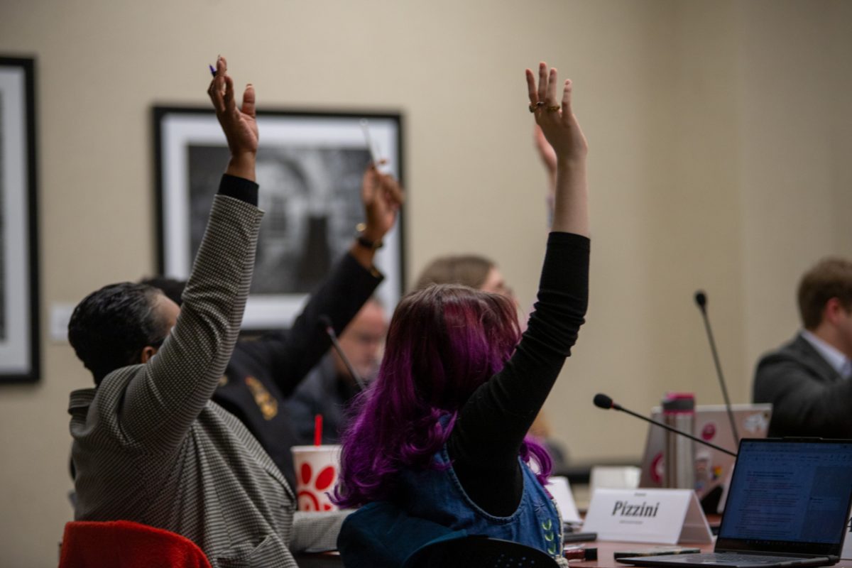 Senators Cynthia Pizzini and Avery Owens raise their hands at a Student Senate meeting on March 11.