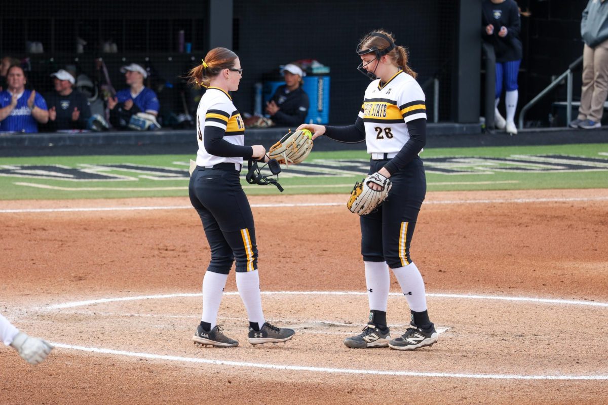 Sophomore Chloe Barber hands the ball to freshman Ryley Nihart. This was the Shockers' only pitching change of the game on March 2.