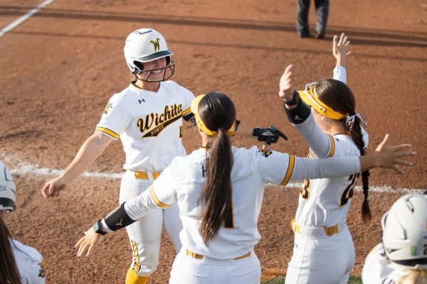 Senior Camryn Compton greets her teammates after making the first run for WSU against the University of Kansas on April 30. The Shockers fell, 5-3, after going nine innings.