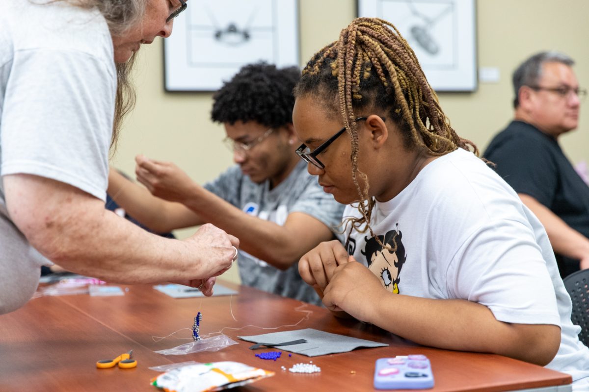 Destiny Summers, a Wichita State student, gets help from beadworker Michelle Conine during the Indigenous Student Collective's spiral stitch beadwork class on May 1. Attendees were given the supplies and instructions to create their spiral stitch bracelets.