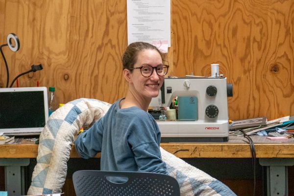 Abby Ausherman turns around while sewing fabric for her exhibition. Ausherman is graduation spring 2025 with a major in Arts.