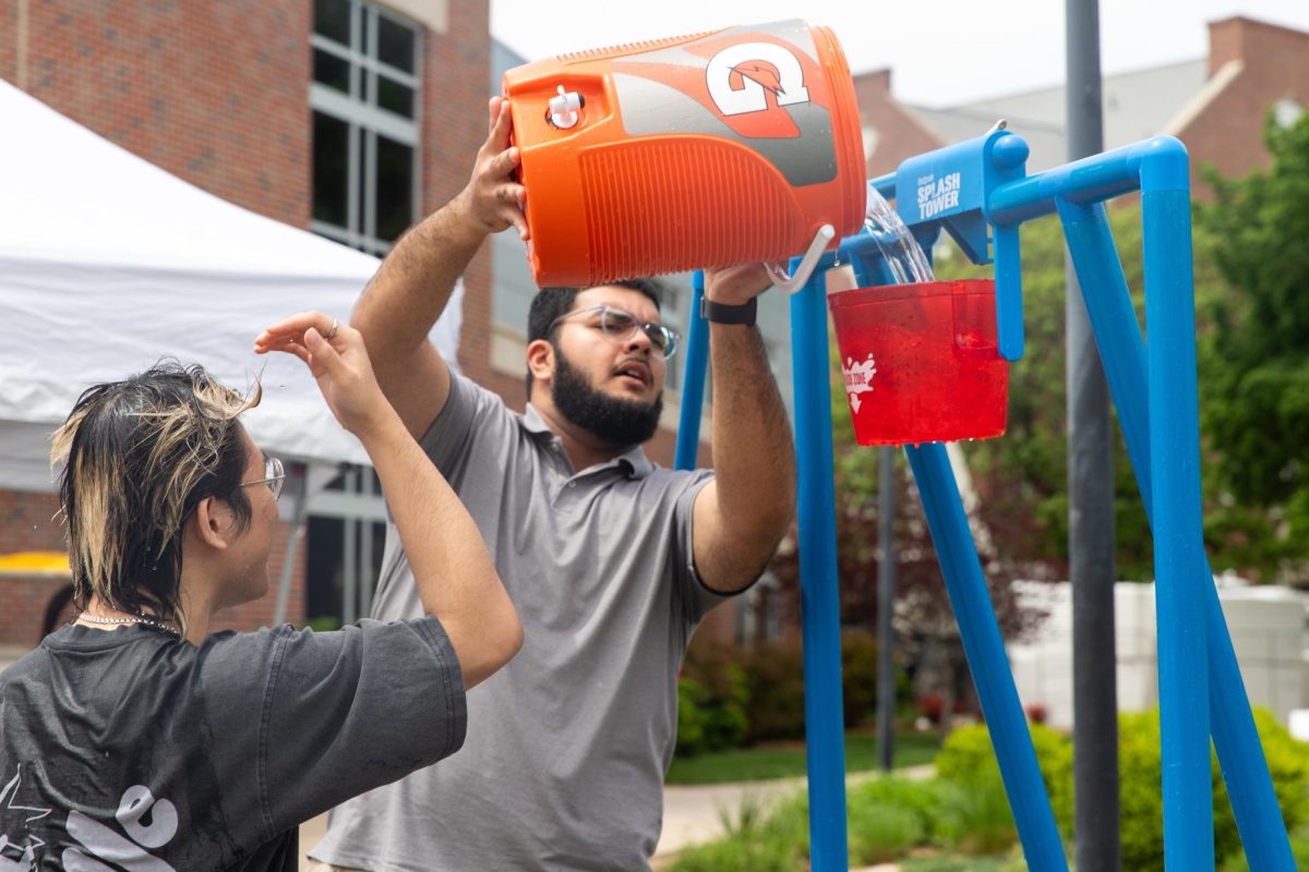 Arib Khan, a first year computer science student, pours icy water from a cooler into a dunk tank bucket during the Asian Student Conference's fundraiser on April 29. Khan refilled the bucket each time an ASC cabinet was doused with water.