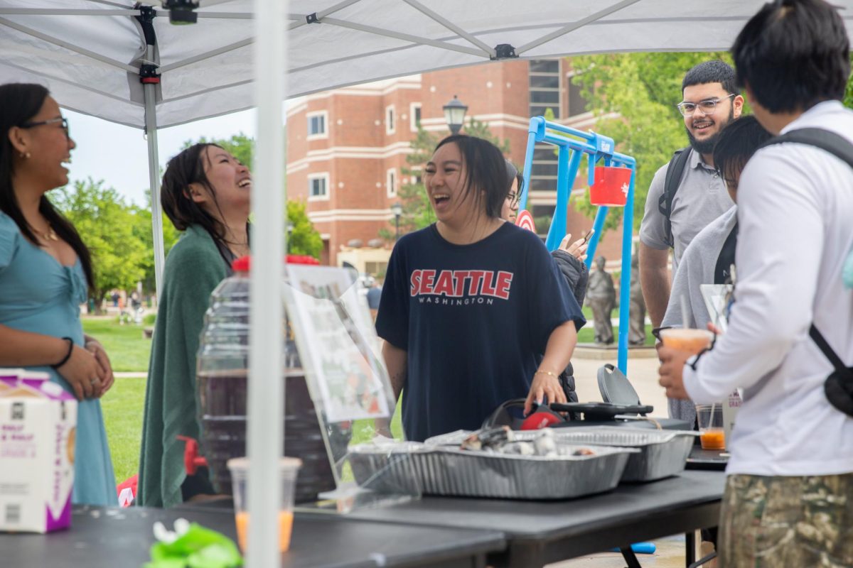 Members of the ASC executive board laugh while dishing up Spam musubi and Thai tea. The group hosted an end-of-the-year fundraiser outside the Rhatigan Student Center on April 29.