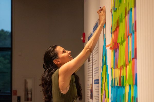 Visitors contribute to a growing mural featuring vibrant paper tiles, assembled under the guidance of museum staff.