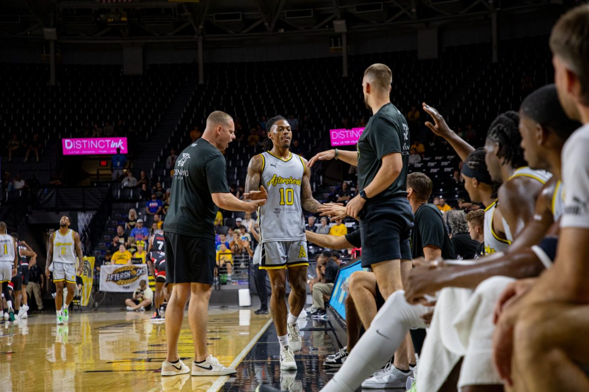 AfterShocks guard Nike Sibande high fives teammates and coaches as he enters the bench on July 18. Sibande scored nine points in 16 minutes against No Excuses.