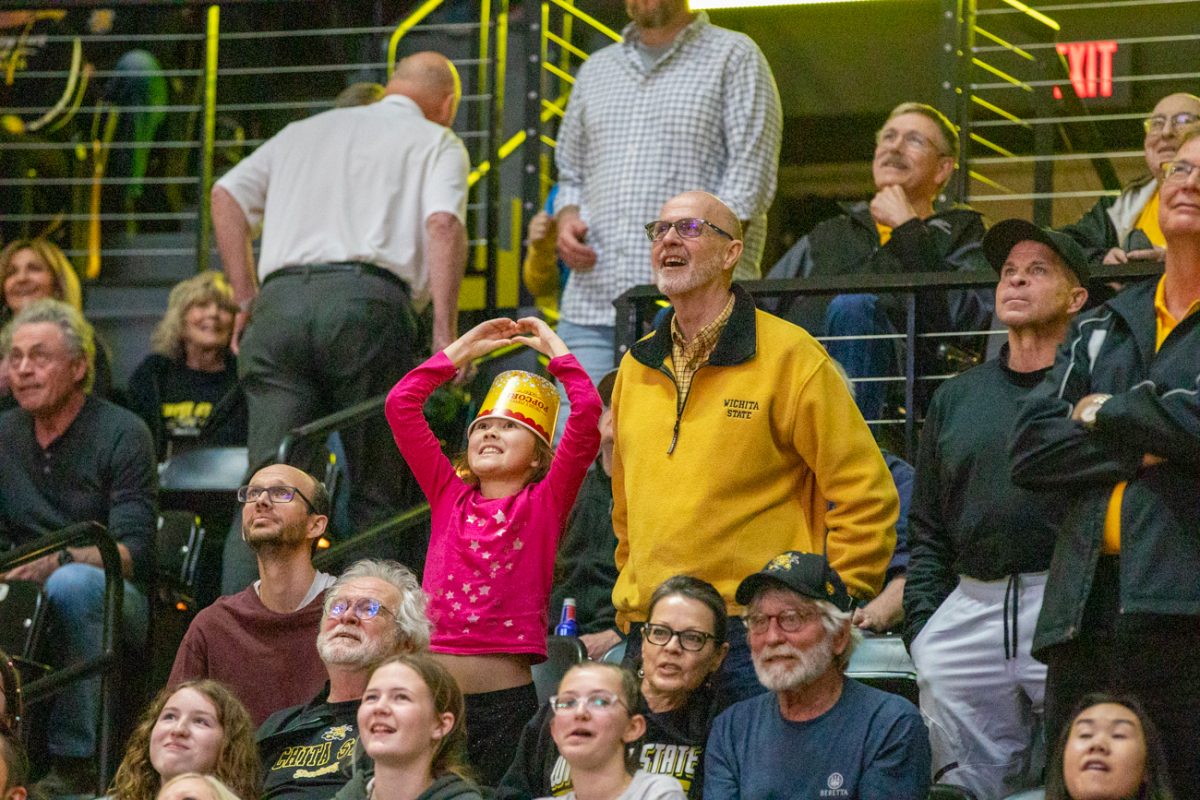 A girl wearing a popcorn bucket puts up a hand heart at a Wichita State men's basketball game on March 2, 2024. The Shockers won their senior night game, 87-66. (File photo)