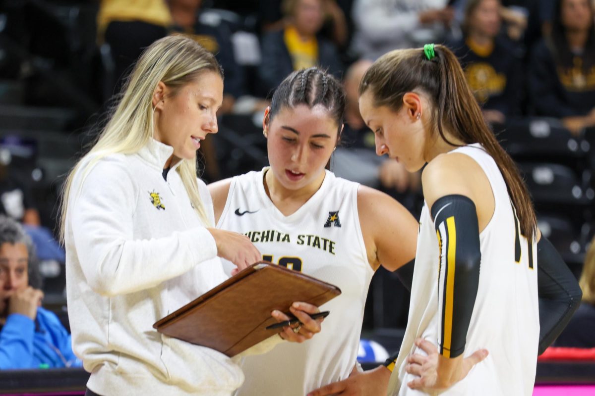 WSU volleyball assistant coach Katie Zimmerman talks with juniors Maddie Wilson and Jordan Heatherly before the second set against Arkansas. The Shockers lost the second set, 25-13, on Aug. 31.