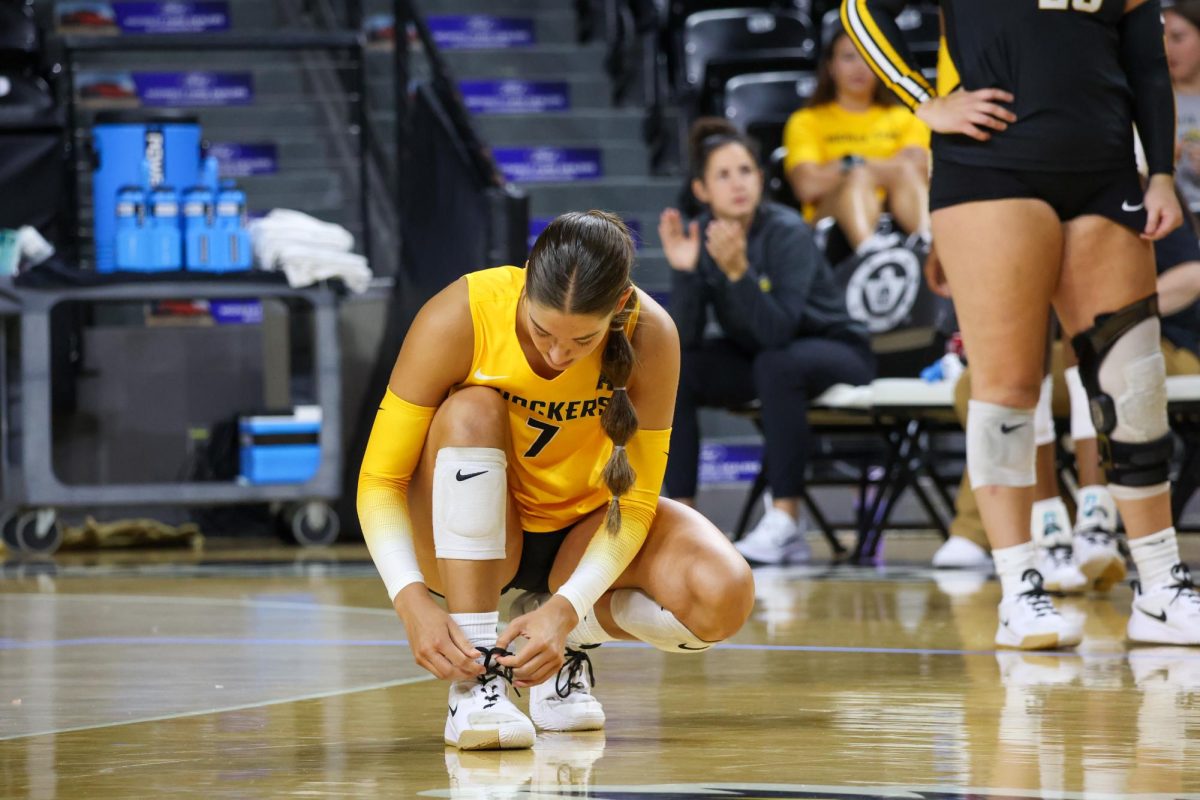 Freshman outside hitter Jenna Cubbage ties her shoes before the Black and Yellow scrimmage starts on Aug. 23. The Yellow team lost, 4-1.