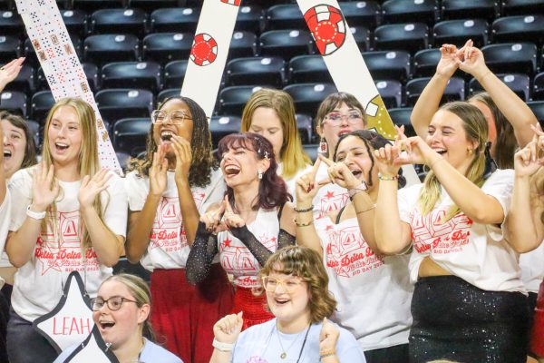 Members of Delta Delta Delta cheering and holding up their sorority sign.