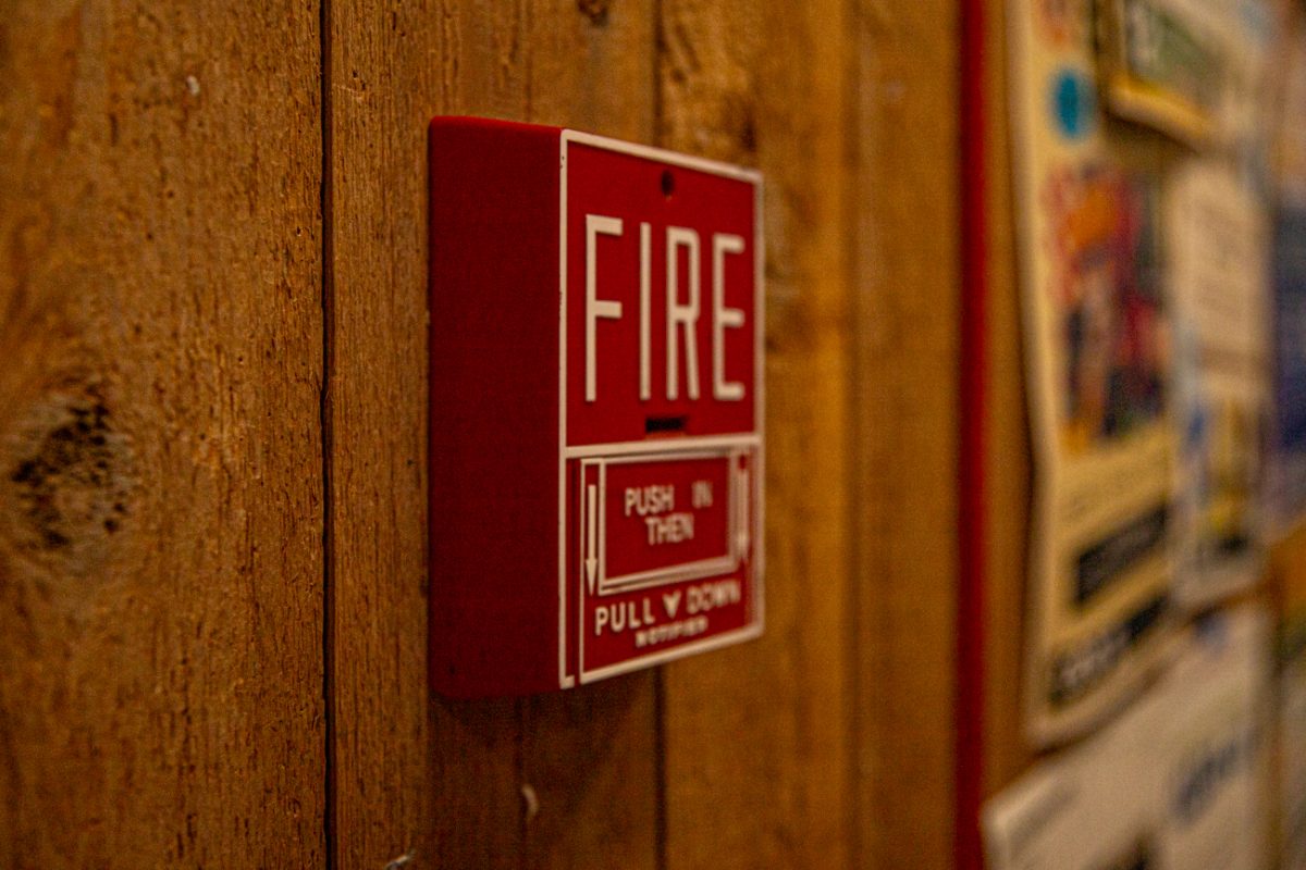 Fire alarm surrounded by posters in McKnight Art Center. The Art Center is connected to the Ulrich Museum of Art