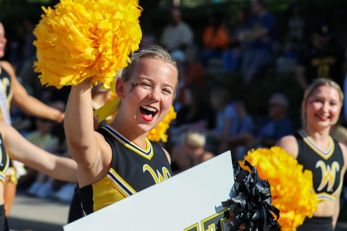 Sophomore Riley Martin waves at the sea of people lined up on the sides of the street. The Shocktoberfest parade was held on Oct. 5 during Family Weekend.