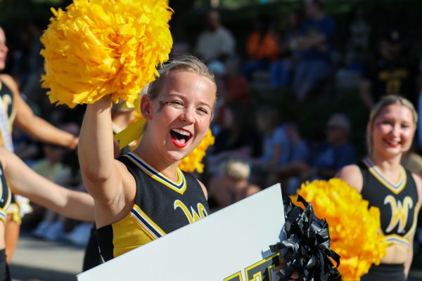 Sophomore Riley Martin waves at the sea of people lined up on the sides of the street. The Shocktoberfest parade was held on Oct. 5 during Family Weekend.