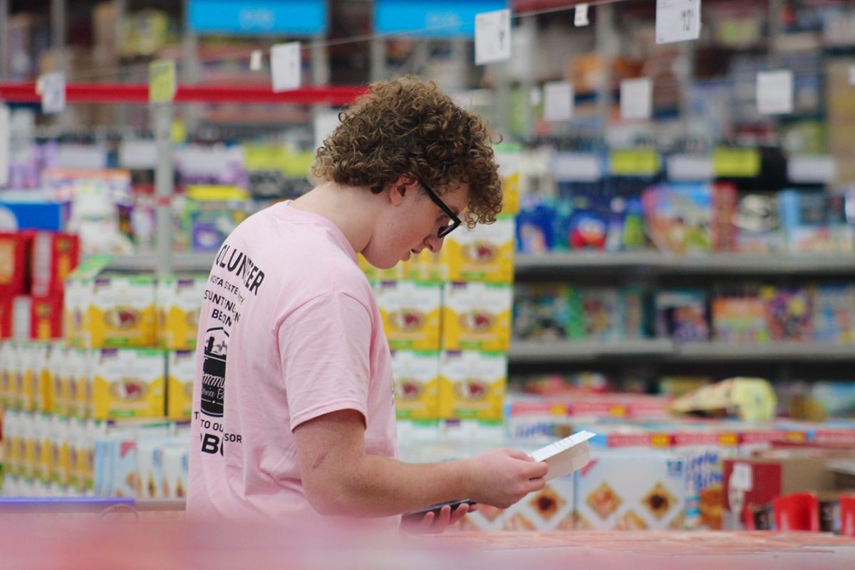 Freshman Learned Kane scans his shopping list and adds up the total amount of money already in his cart. The volunteers are splitting a large list with a budget of $5,000.