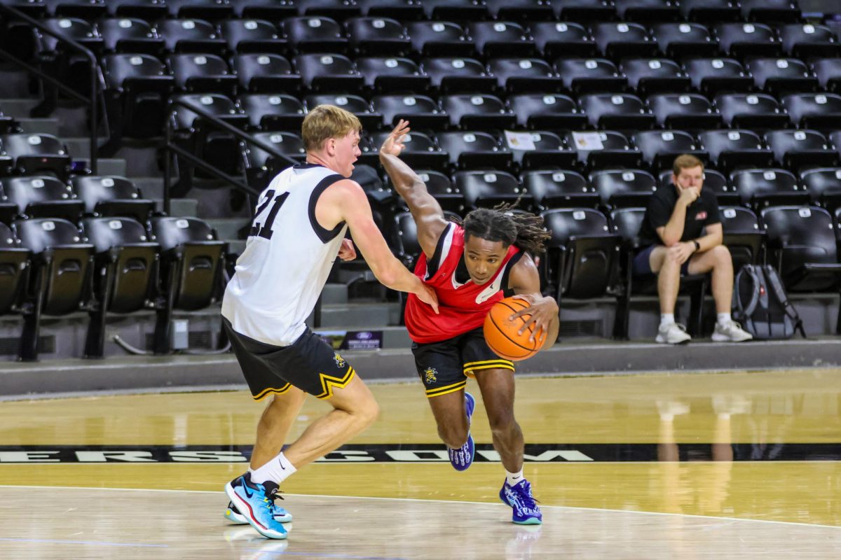 Guard Pierre Couisnard dribbles the ball past forward Henry Thengvall. Wichita State's men's basketball team held an open practice on Sept. 18.