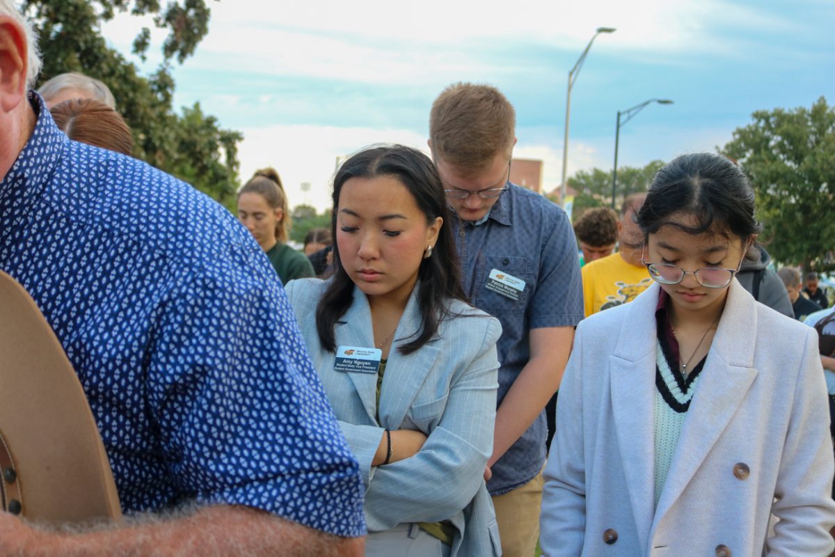 Student Government Association President Jia Wen Wang (right) and Vice President Amy Ngyuen (left) bow their heads to pray with the crowd at Memorial '70 ceremony on Oct. 2, 2025, in Wichita, Kansas.