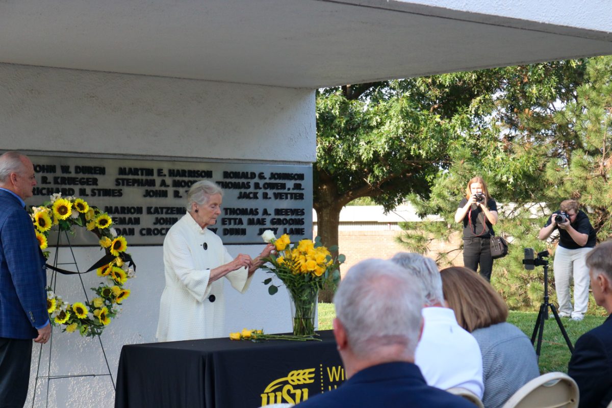Relatives of former Wichita State President James Rhatigan places a white rose in the vase to honor him during the Memorial '70 ceremony on Oct. 2, 2025, in Wichita, Kansas. Rhatigan passed away in October 2024.