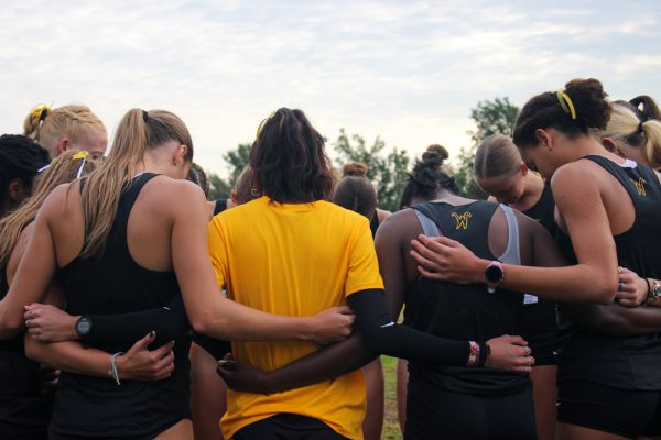 Wichita State's women's cross country team huddles before the women's 5-kilometer race at the JK Gold Classic on Saturday, Sept. 6, 2025, at LW Clapp Park. The women's team placed third out of nine teams during the race.