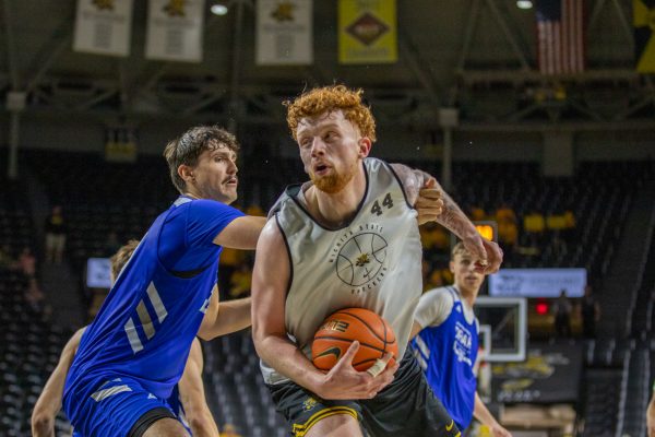 Wichita State men's basketball junior Will Berg (44) holds on to the ball as a Drake Bulldog tries to snatch it in the paint on Saturday, Oct. 11, 2025, at Koch Arena. Berg is currently the tallest player at Wichita State at 7-foot-2.