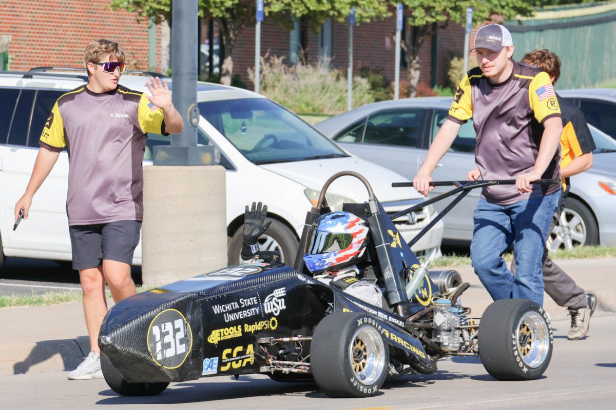 The Wichita State Formula SAE team pushes their car down Mike Oatman Drive in the 2025 Shocktoberfest parade. Students on the Shocker Racing team build, test and race formula cars. 