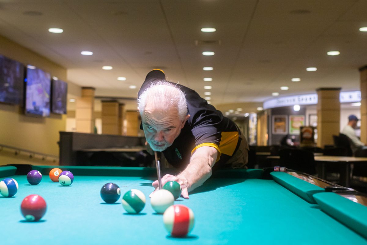 Terry Young lines up a shot on a pool table in Shocker Grill and Lanes. Young has taught the billiards class for 30 years.