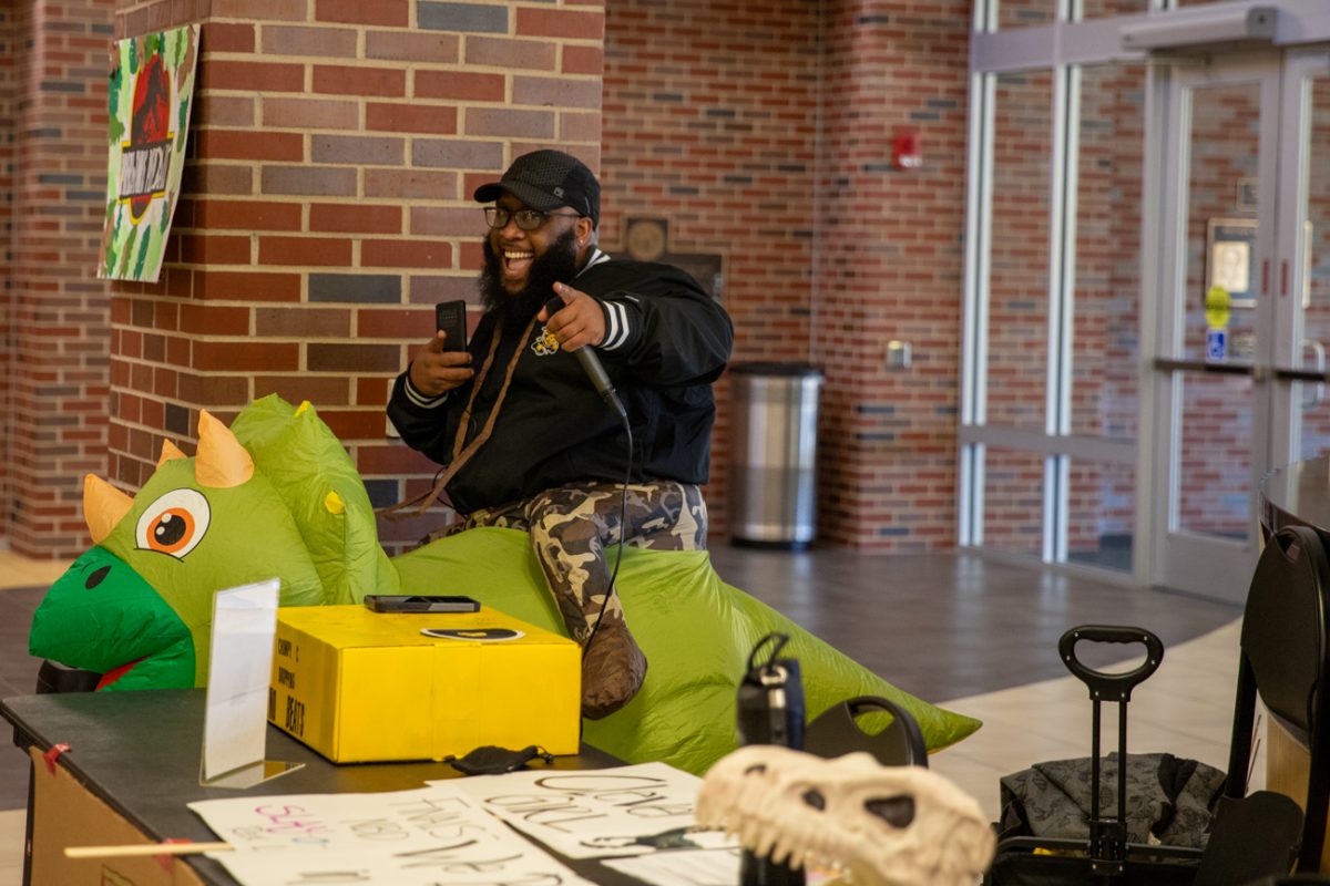Courtney Lockhart, lead case manager and advocate of the Student Outreach Service, smiles and points. Lockhart's alias during the Dino Pep Rally was Chompy C, a dinosaur DJ dropping "dino" beats.