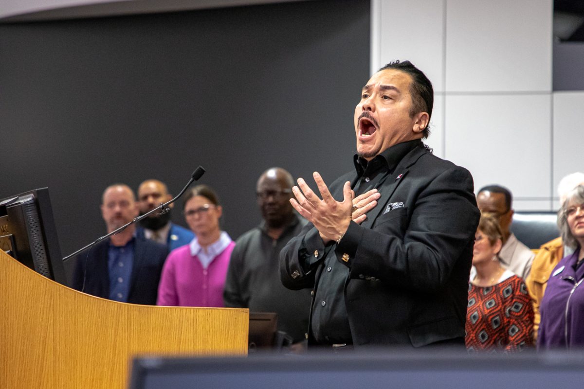 Hugo Castillo sings "Never Walk Alone" at the start of the interfaith prayer service. The service was hosted in the city council chambers. (KMUW)