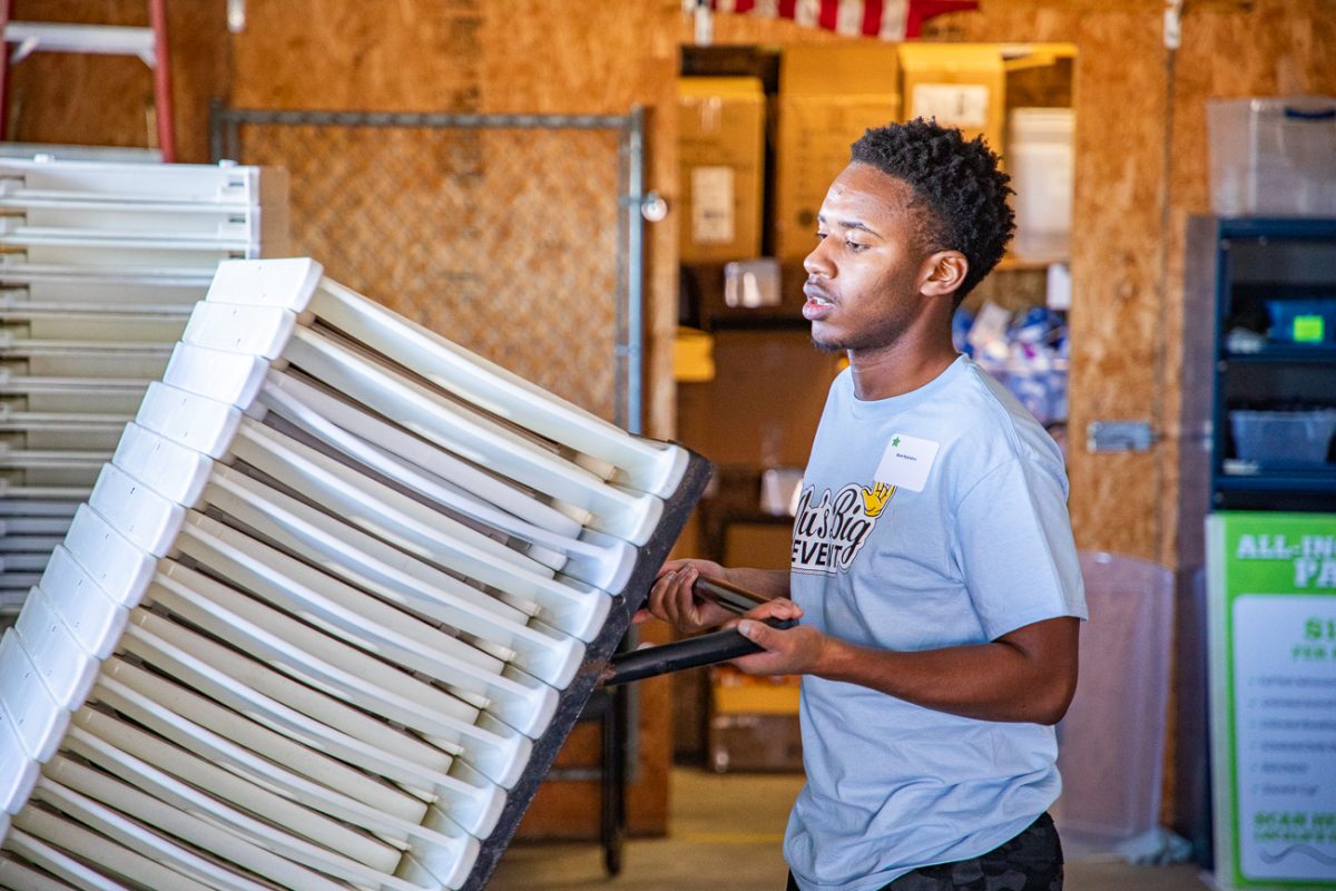 Brett Nyandoro wheels a stack of cleaned chairs into storage. The event began at 9:30 a.m.