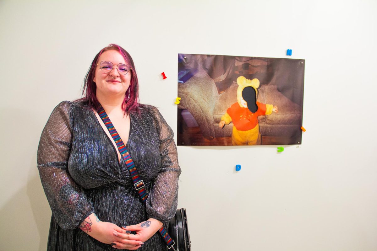 Artist Zelda McAfee poses next to Picture of Innocence, 2026, a burned inkjet print, during the opening night of their solo BFA exhibition at Wichita State University’s ShiftSpace Gallery on Feb. 6.