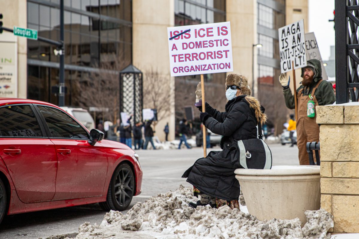 A woman sits and protests Immigration and Customs Enforcement on the corner of Douglas and Broadway (File photo).