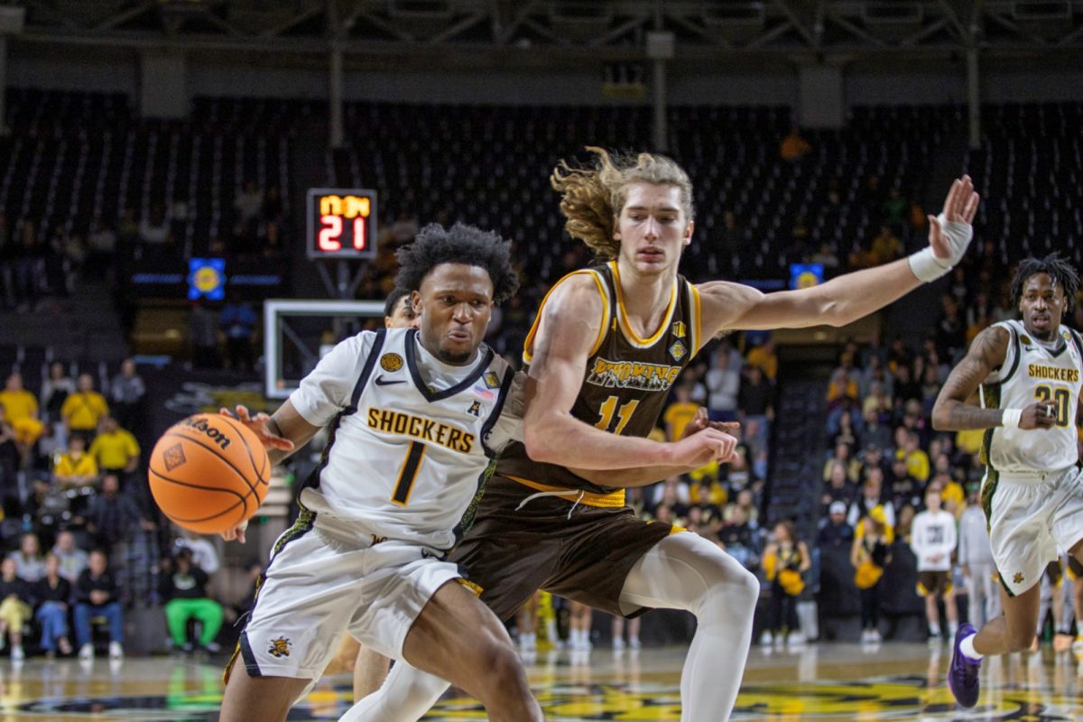 Wichita State men's basketball senior guard Kenyon Giles (1) bumps a Wyoming Cowboy during the first round of the NIT on March 17 at Koch Arena. The Shockers played their third game in four days against Wyoming.