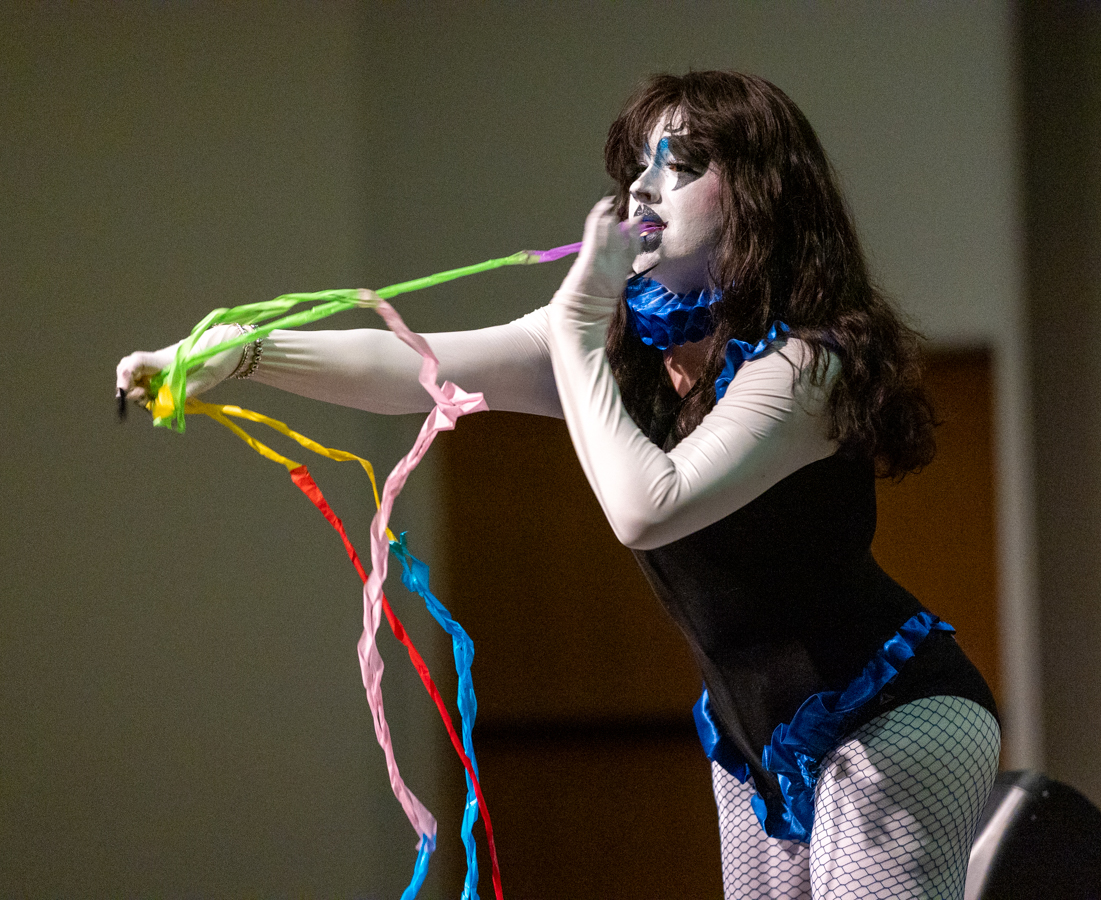 Bailey Seer pulls scarves out of their mouth as part of their performance. Seer's other prop was a handheld fan labeled with the word "CUNT."