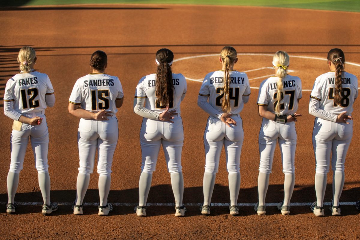 The Wichita State softball team holds the Shocks Up sign behind their back as the national anthem plays before the game against Tulsa on April 2 at Wilkins Stadium. (File photo)