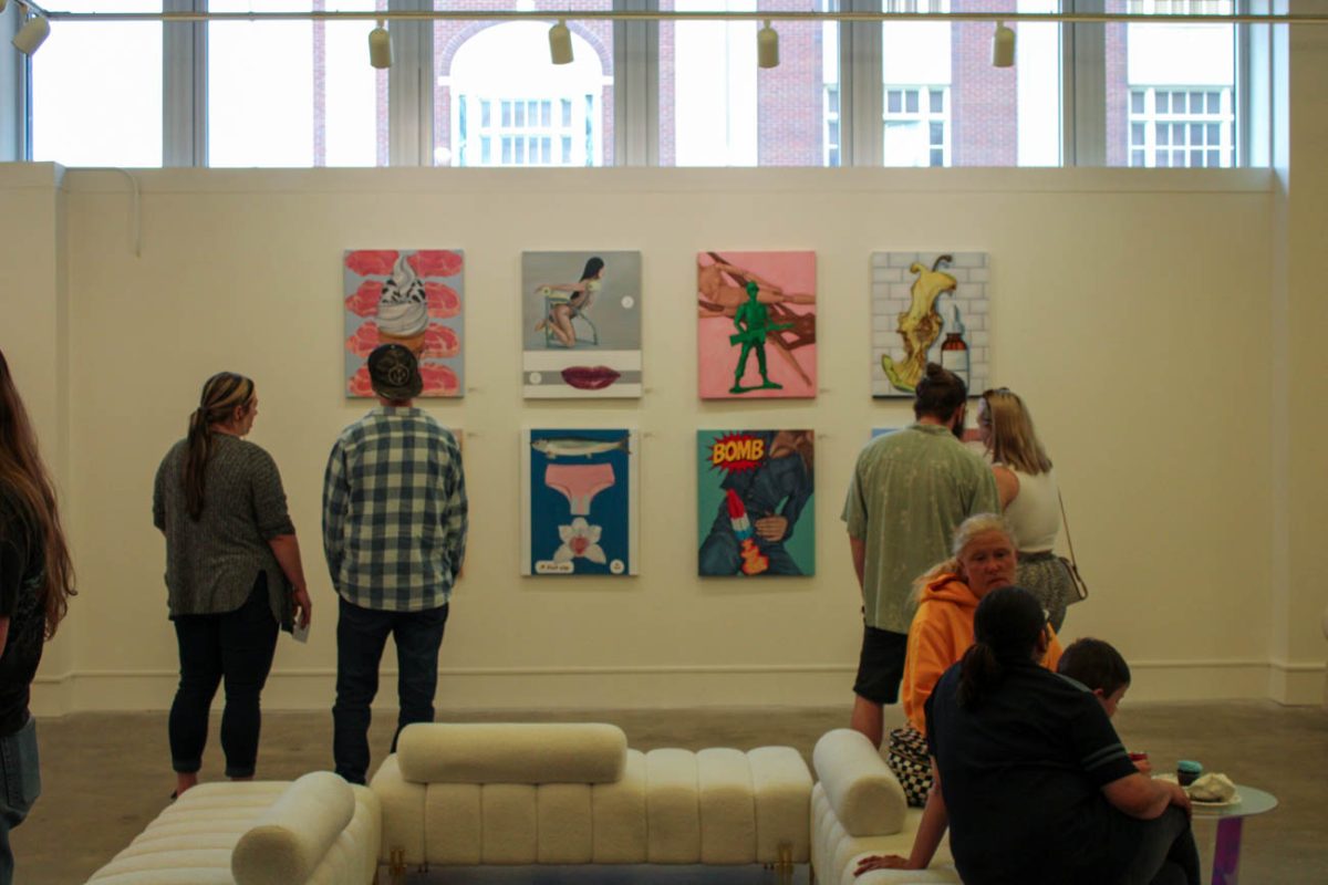 Attendees of the thesis exhibitions look at the work of Madison Mullen. The three exhibits on display in Harvester Arts and ShiftSpace will be on display through April.