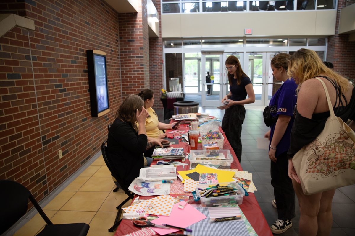 Students gather at a crafts table. The supplies available ranged from colored paper to newspaper.
