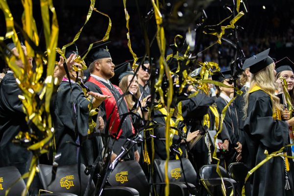 Graduates celebrate as black and yellow streamers fall around them at the end of their commencement ceremony.