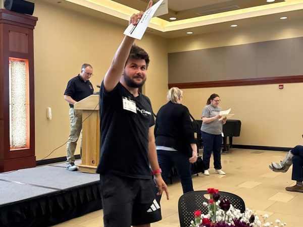 Multimedia reporter Mack Smith points toward members of The Sunflower after winning an award at the 2026 Kansas Collegiate Media Conference. (Photo courtesy of Amy DeVault.)