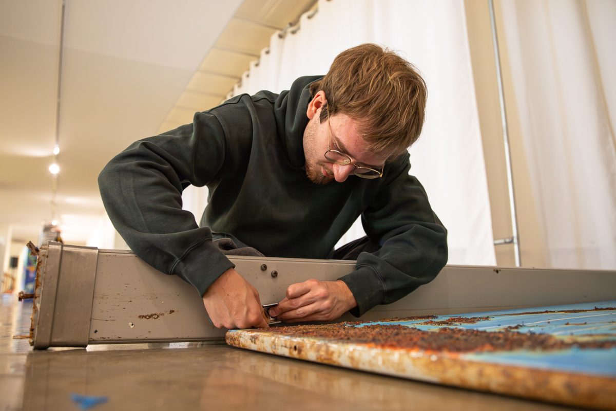 Noah Hutchinson assembles the walls of a bathroom stall that he build for his senior exhibition.