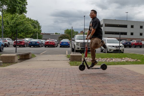 Multimedia reporter Evan Tong does a bunny hop on a scooter in front of the Elliott School of Communication.