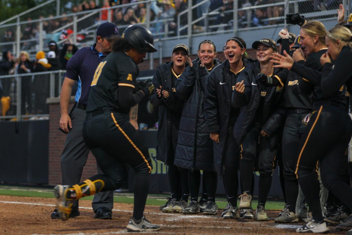 Wichita State softball sophomore Ausha Moore (81) is surrounded by teammates at home plate after hitting a three-run home run against Memphis on May 1 at Wilkins Stadium. Moore hit 1-for-3 during the win.